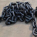 Black painted marine anchor chain piled on workshop floor