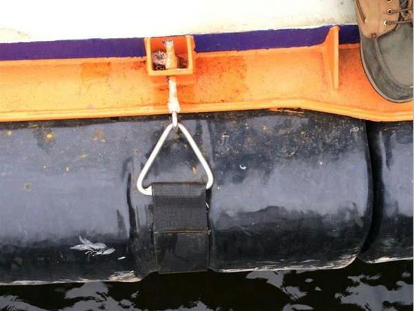 EVA yacht fender fixed with black mounting strap and metal triangular ring on boat side