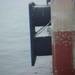 Fixed dock rubber fender with frontal panel and chains installed on a quay wall for berth protection
