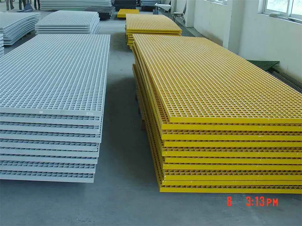 Yellow and grey GRP FRP grating panels stacked in a workshop for marine and industrial flooring applications
