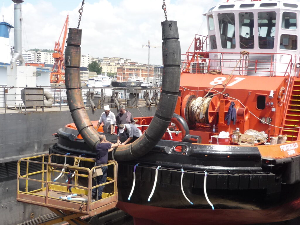 Grooved cylindrical rubber fender being installed on tugboat for bow protection