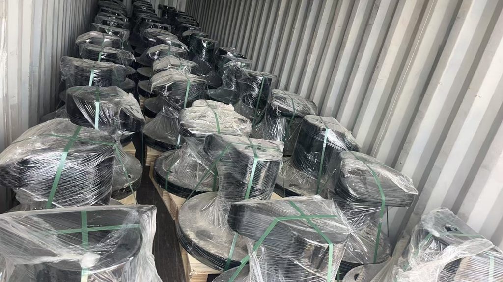 Rows of wrapped black mooring bollards arranged on pallets inside a shipping container