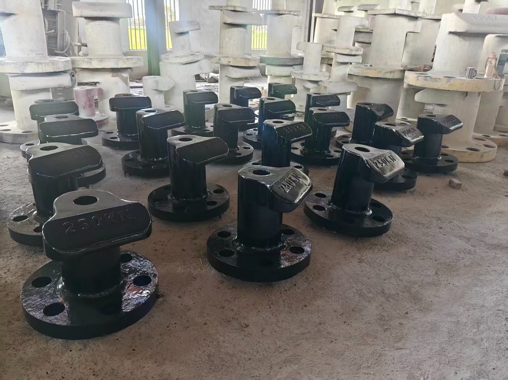 Rows of 250 kN mooring bollards with freshly applied black protective paint drying in the workshop