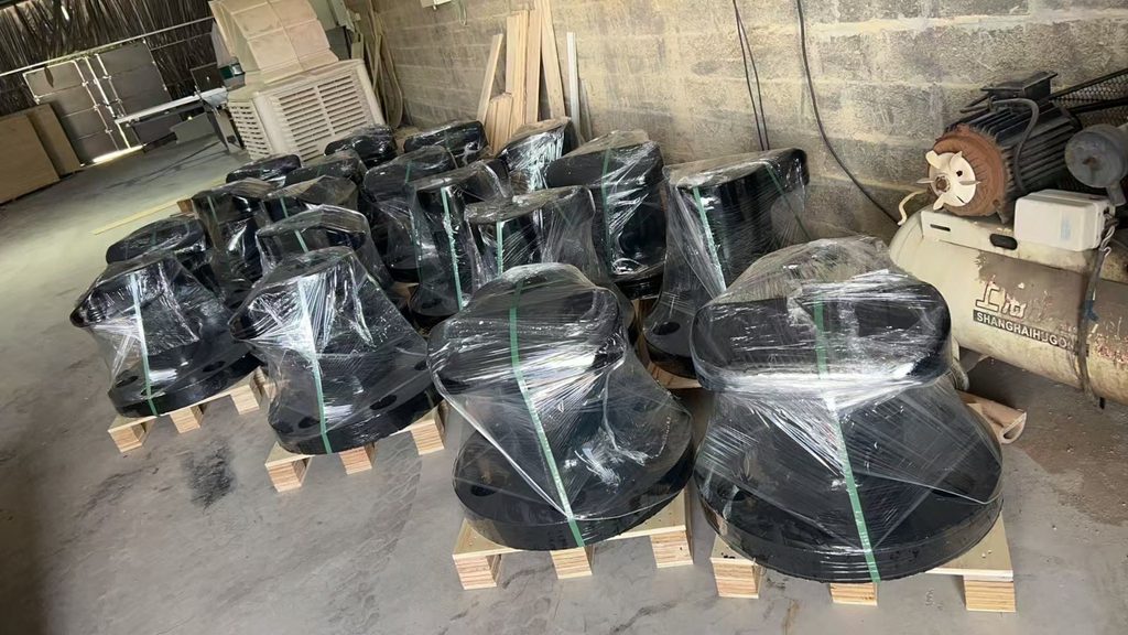 Black mooring bollards wrapped in clear film and strapped to wooden pallets